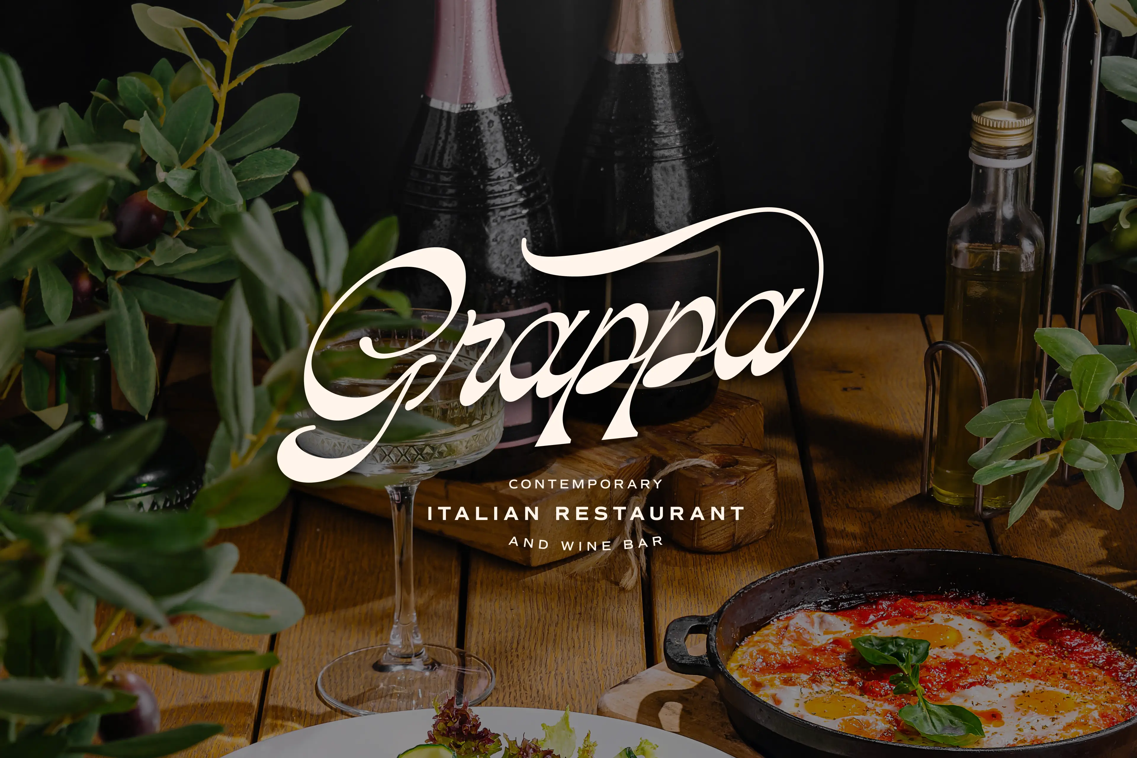 The logo of Grappa Contemporary Italian Restaurant and Wine Bar overtop of an image of a high-end Italian dinner spread of pasta, wine, and olive oil